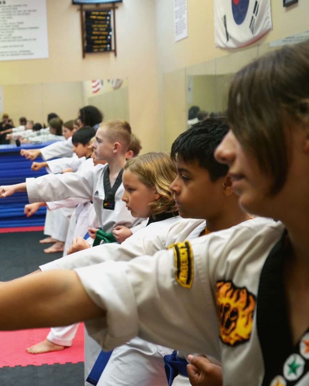 Kids and teen students in white doboks practicing a punching technique together
